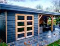 Houten schuur met dubbele glasdeuren en een overkapping met loungeset